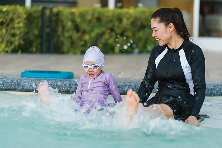 Little girl playing in water with mother